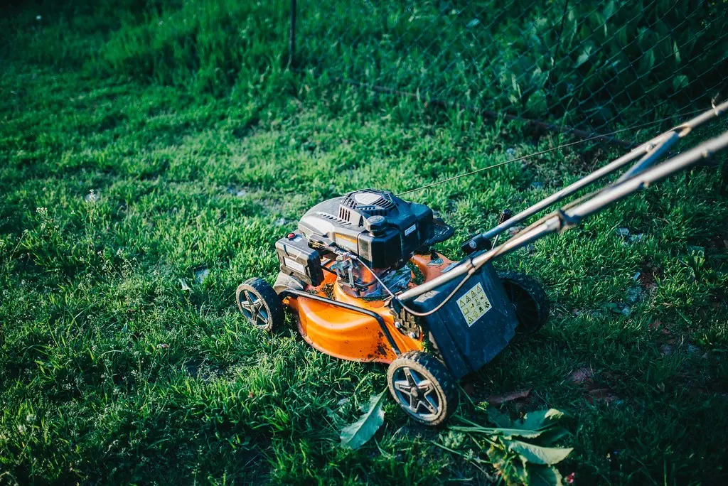 An orange walk-behind mower sitting on a green lawn.